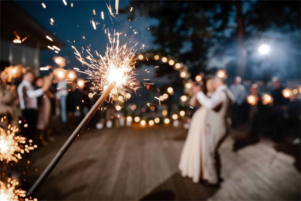 Sparkler in hands on a wedding - bride, groom and guests holding sparkler